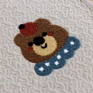 Detailed view of thick chair cushion with cute tufted bear embroidery, soft fabric material.