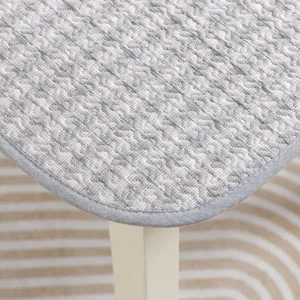 Close-up of thick quilted chair cushion with grey stripe pattern, soft textile texture.