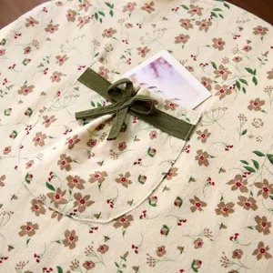 Dettaglio tasca grembiule con stampa floreale, cotone di qualità con fiocco verde e stile retrò.