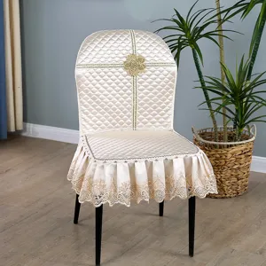 Vue détaillée de la housse de chaise de salle à manger matelassée beige avec bordure en dentelle.