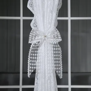 Vue détaillée de l'attache de rideau en dentelle blanche avec nœud et perle.