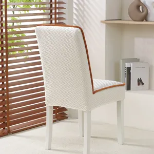 Detailed view of white textured elastic dining chair cover with brown piping for modern home.