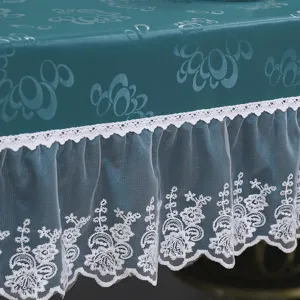 Primo piano di una tovaglia scura con elegante ricamo in pizzo bianco e balza in tulle.