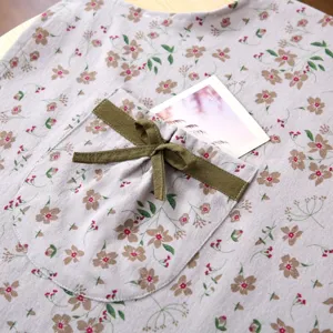 Primo piano dettagliato della tasca del grembiule in tela floreale con fiocco verde.