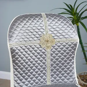 Housse de chaise matelassée grise avec ruban en dentelle et fleur dorée, élégante.