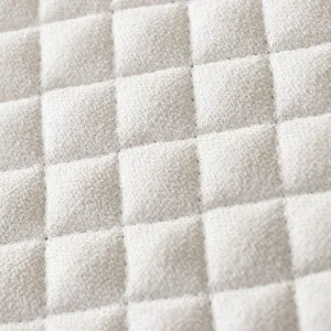 Close-up detail of thickened grid quilted chair cushion cover fabric texture in light beige color.