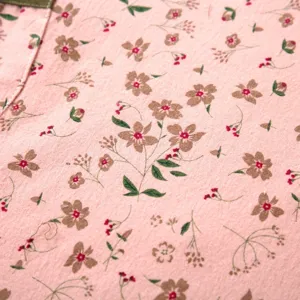 Dettaglio tessuto grembiule tela floreale rosa, traspirante e resistente per cucina.
