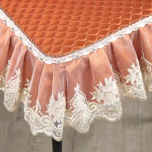 Vue rapprochée de la housse de chaise matelassée orange avec broderie de dentelle blanche.