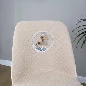 Beige curved dining chair cover detail, featuring elegant embroidered deer and lace floral wreath.