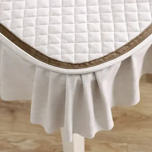 European style quilted dining chair cushion with brown velvet trim and pleated skirt detail.