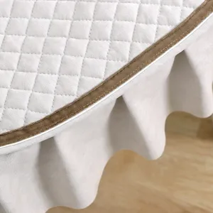 Close-up of European quilted chair cushion with soft grey fabric, brown piping and ruffled skirt.