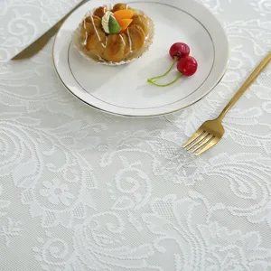 Detailed view of elegant white lace tablecloth featuring delicate floral patterns for home decor.