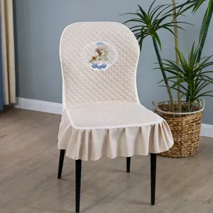 Détail de housse de chaise de salle à manger matelassée avec broderie cerf et dentelle.