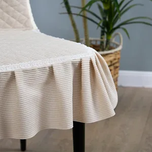 Détail de housse de chaise de salle à manger en velours côtelé beige, bordure en dentelle.