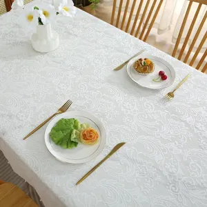 White lace tablecloth detailed view showcasing delicate floral pattern design on a dining table.