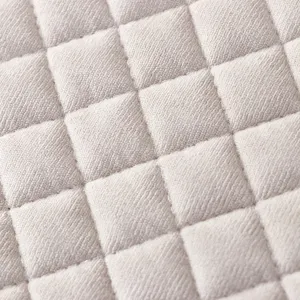 Vue rapprochée détaillée de la texture de tissu matelassé beige en losanges pour housse.