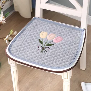 Detail shot of a thick quilted chair cushion featuring elegant tulip embroidery and clean edge binding.