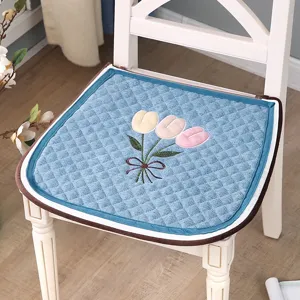 Blue quilted chair cushion featuring cute tulip embroidery, cozy dining room seat pad.