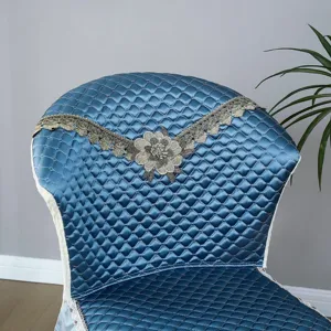 Housse de chaise matelassée bleue avec broderie florale en dentelle en détail.