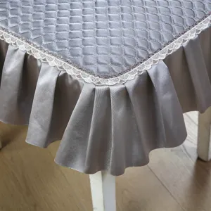 Gros plan sur la housse de chaise matelassée grise avec bordure en dentelle et jupe en satin.