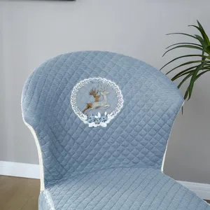 Gros plan de la housse de chaise matelassée bleue élégante avec broderie délicate de cerf et fleurs.