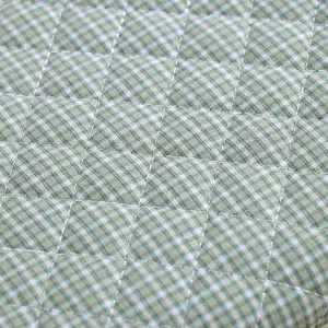 Gros plan sur le tissu à carreaux vert et blanc matelassé avec une texture de surpiqûre.