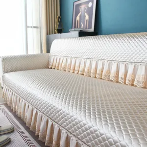 Close-up detail of the quilted champagne sofa cover with elegant lace fringe and texture.