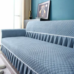 Blue quilted sofa cover with elegant ruffled skirt, breathable and slip-resistant design.