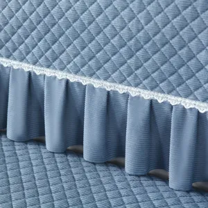 Detailed view of quilted sofa cover with elegant ruffled skirt and lace trim for cozy home decor.