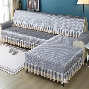Detailed view of quilted grey sofa cover featuring elegant lace trim in living room setting.