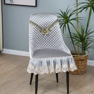 Detailed view of grey quilted dining chair cover with elegant lace embroidery and floral accent.