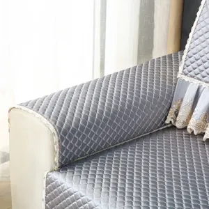 Detailed view of quilted gray sofa cover featuring elegant lace trim and soft texture.