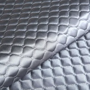 Detailed close-up of grey quilted sofa cushion fabric with padded geometric texture.
