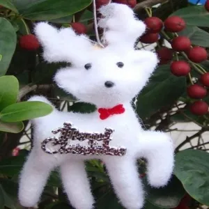 Gros plan d'un renne de Noël en polaire blanche suspendu à une plante aux baies rouges