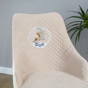 Vista dettagliata della fodera per sedia trapuntata beige con ricamo di cervo e pizzo.