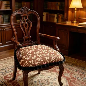 Detailed view of vintage European style wooden armchair with floral cushion and fringe trim.