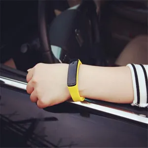 Detail view of a stylish yellow LED sports bracelet worn on a wrist in a car setting