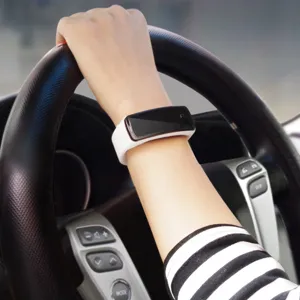 Nahaufnahme eines schlanken weißen LED-Digital-Sportarmbands, das beim Autofahren getragen wird
