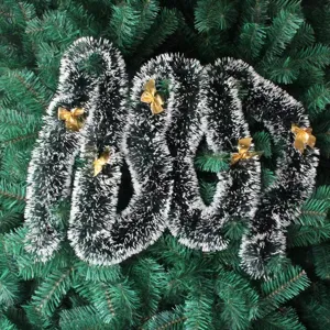 Detailed macro view of dark green Christmas garland with white tips and golden bows