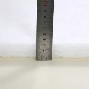 Détail du matériau de rembourrage de coussin blanc épais, montrant la texture douce avec règle.