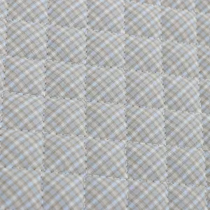 Gros plan du tissu de coussin matelassé à carreaux, texture douce et coutures fines.