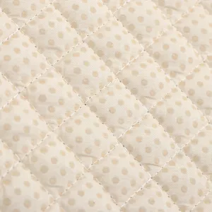 Gros plan détaillé de la texture en tissu de coussin à pois beige matelassé et coutures.