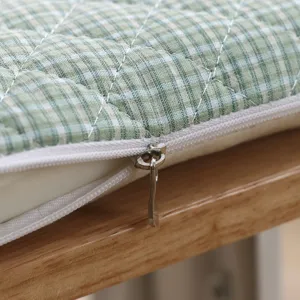 Detailed view of green plaid cushion showing soft quilted fabric texture and neat zipper design.