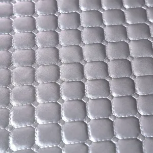 Gros plan détaillé de tissu matelassé gris argenté avec motif de grille et coutures.