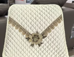 Close-up detail of quilted chair cover with elegant golden lace and floral embroidery.