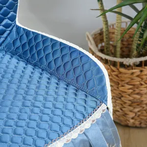 Détail de la housse de chaise bleue matelassée avec bordure en dentelle et texture douce.