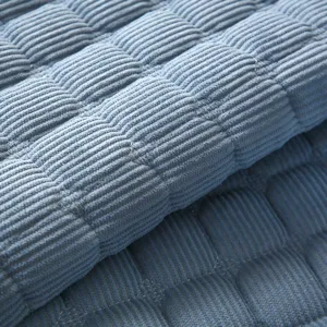 Blue corduroy quilted cushion cover close-up, showing thick soft fabric texture and stitching details.
