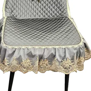 Grey quilted dining chair cover with elegant lace trim and golden floral embroidery. Perfect home decor.