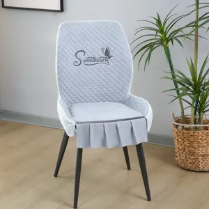 Détail de housse de chaise de salle à manger matelassée grise avec broderie et volants.