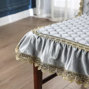 Detalle de funda de silla de terciopelo gris, cojín acolchado con ribete de encaje dorado.
